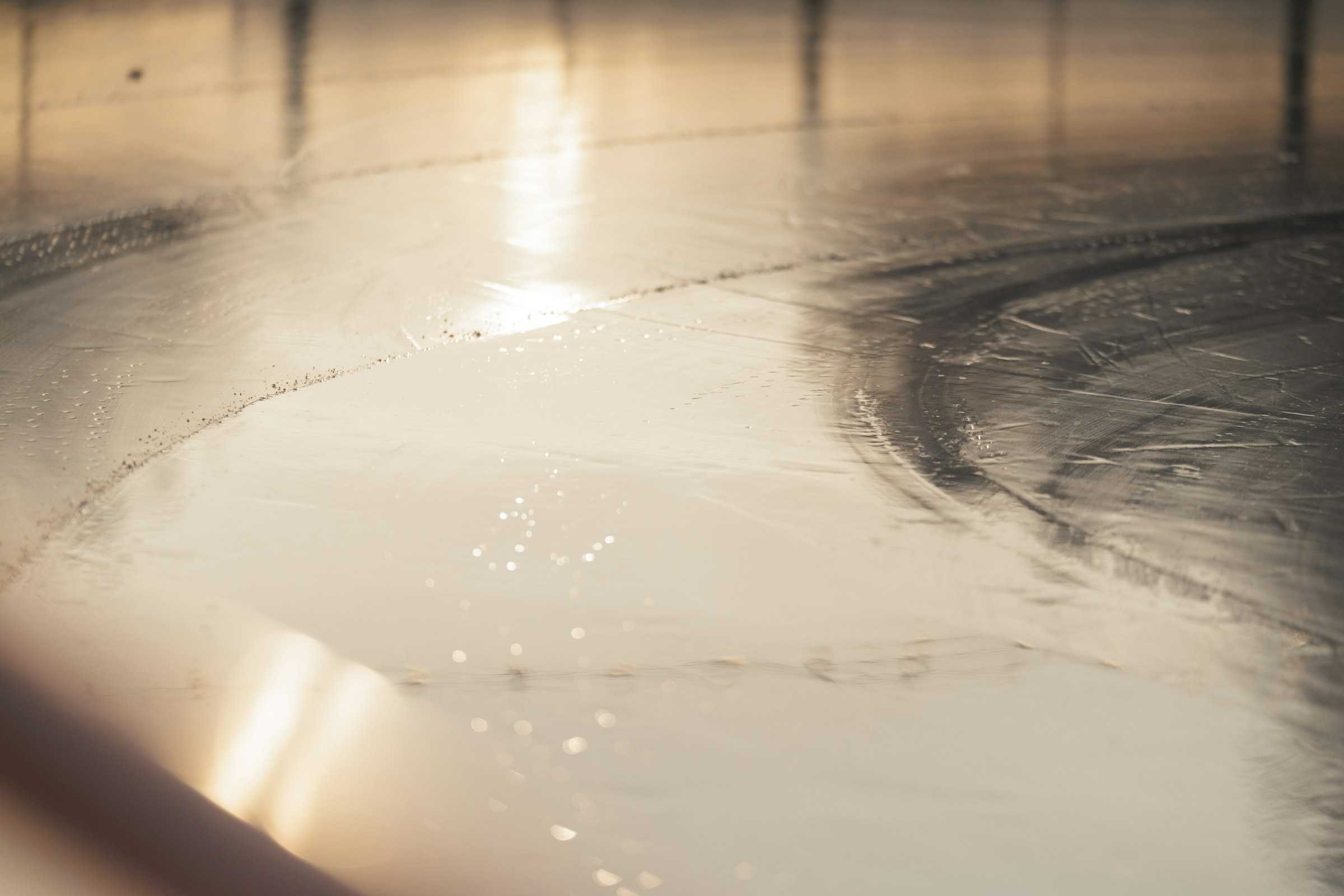 Resina recém-aplicada espalhando-se sobre o piso, com reflexo de luz