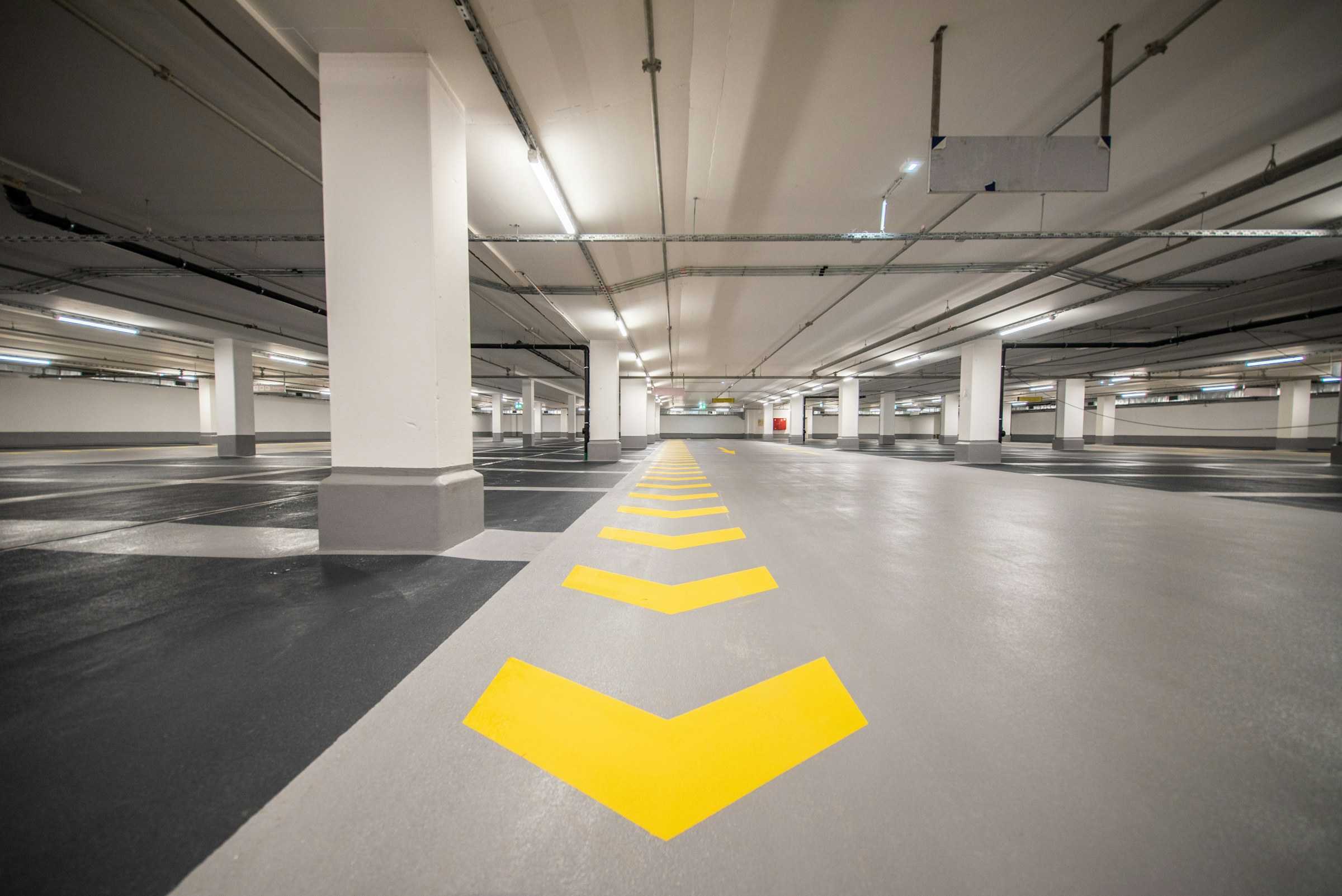 Setas amarelas de direção pintadas no piso de uma garagem coberta